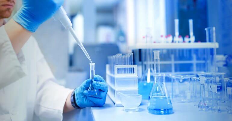Técnico con guantes calibrando una balanza analítica de precisión en el laboratorio