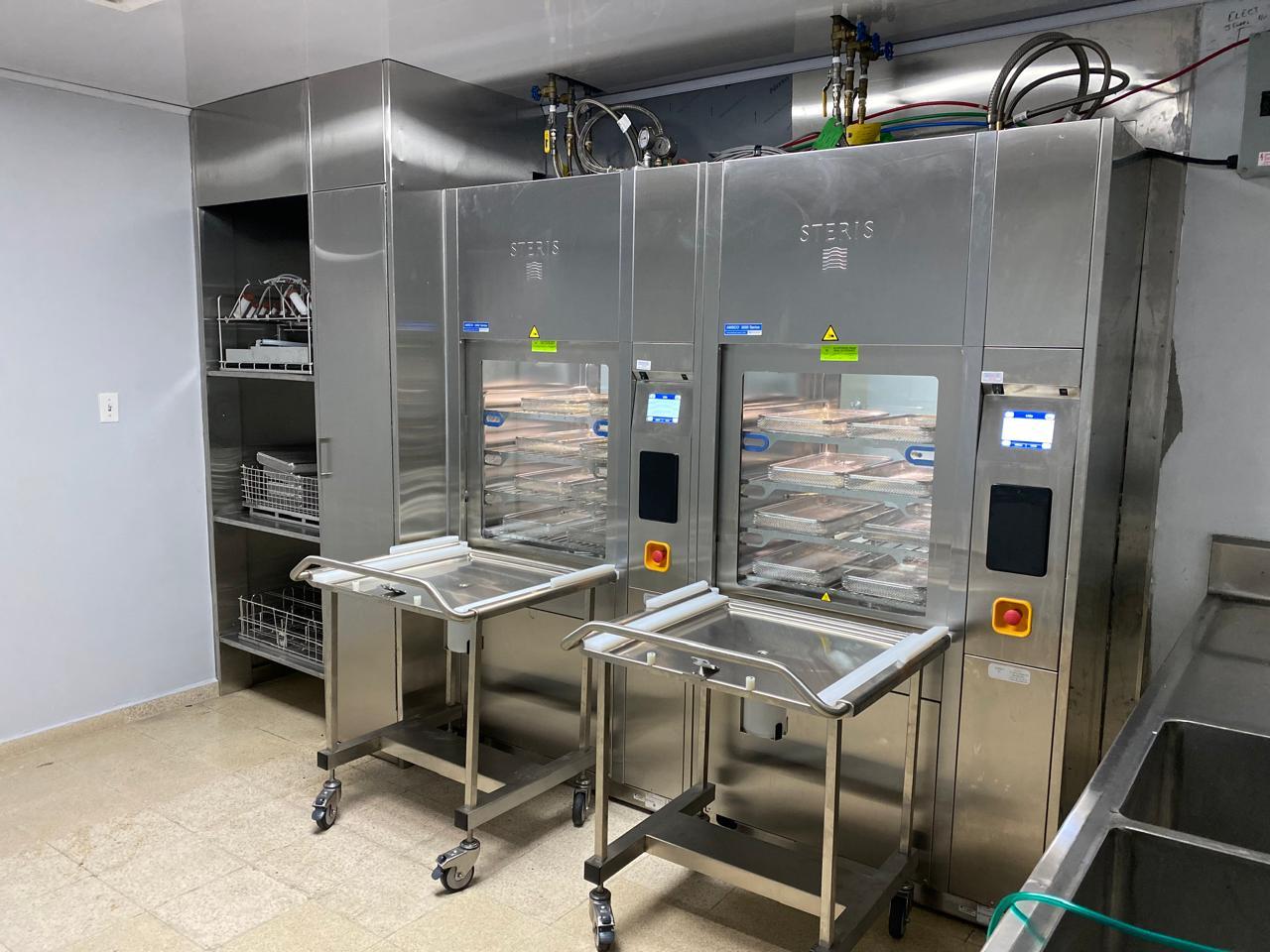 Sala hospitalaria vacía con varias camas alineadas y equipo médico de soporte
