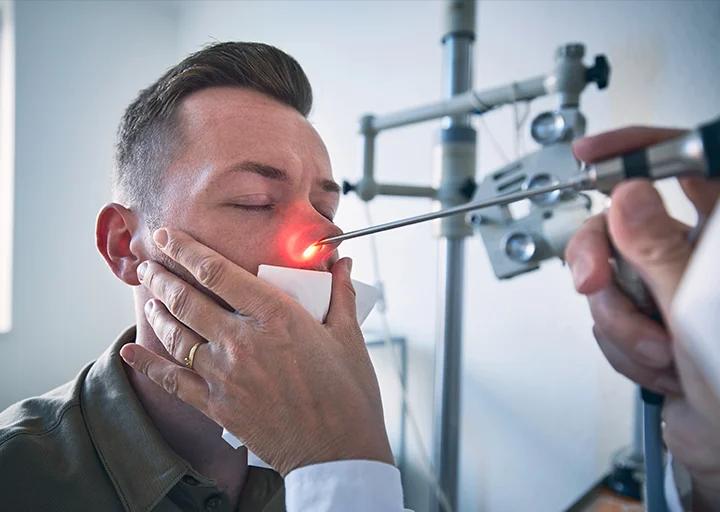 Médico examina el oído de un niño con un otoscopio en un consultorio